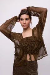 Camisa color marrón con brillos dorados, escote cuadrado con volados y lazo ajustable, mangas largas abullonadas y confección en chiffon.