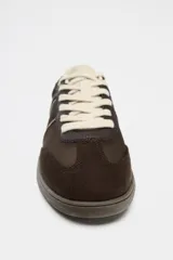 Zapatillas deportivas marrones con detalles en color crema y suela plana.