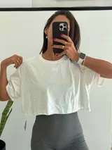 Remera corta de algodón blanca, con cuello redondo y manga corta holgada. Presenta un pequeño logo bordado en el pecho.