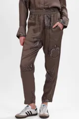 Pantalón de seda cupro color verde con estampado de leopardos alados, corte recto, bolsillos al frente y elástico en la cintura.