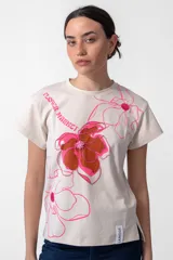 Remera color crudo de algodón con cuello redondo y mangas cortas. Estampa exclusiva "Flower Market" con flores en tonos rosa y marrón.