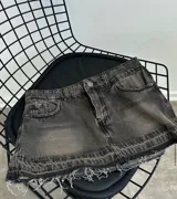 Minifalda de jean color gris oscuro con efecto desgastado, tiro bajo, corte ajustado y ruedo desflecado.