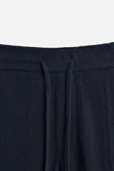 Pantalón azul marino de corte relaxed fit, confeccionado en tejido con mezcla de algodón. Presenta cintura elástica ajustable con cordón, bolsillos frontales y detalle de bolsillo trasero de plastrón.