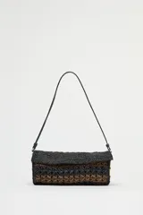 Bolso de hombro con cuerpo trenzado en color negro y marrón. Tiene detalle metálicos circulares en los laterales, asa de hombro, bolsillo interior con cremallera y cierre mediante solapa y cremallera.