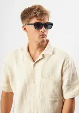 Lentes de sol Eco Shades modelo Romano con montura cuadrada azul traslúcido y lentes grises. Fabricados con acetato biodegradable y lentes de PMMA reciclado.