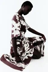 Vestido midi camisero color marrón con estampado floral blanco, cuello camisero, botonadura frontal y mangas cortas. Incluye cinturón extraíble para atar.