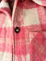 Campera oversize de paño con diseño cuadrillé en tonos rosa y crudo, corte recto y amplio, con botones frontales, bolsillos laterales y forro interior.