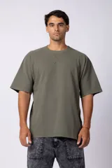 Remera verde militar de algodón grueso con tela micropanal, corte oversized, cuello redondo con costura en “X” y mangas cortas. Sin logos al frente.