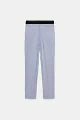 Pantalón tobillero celeste con tiro medio, cintura elástica en la espalda, bolsillos delanteros y falsos bolsillos de vivo en la espalda. Tiene aberturas laterales en el bajo y cierre frontal con cremallera, botón interior y gancho.