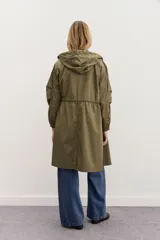 Campera impermeable negra a la rodilla de corte amplio, con cierre frontal, capucha, bolsillos y elástico en los puños. Cuenta con cordones de diseño personalizado en la cintura y la capucha, y detalles en símil cuero en bolsillos y cierre delantero.