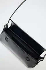 Bolso de hombro negro acharolado con solapa y asa ajustable. Cierre con imán.