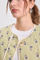 Chaqueta acolchada color verde claro con rayas verticales y pequeños estampados florales en tonos azules y verdes. Tiene cuello redondo, cierre frontal con botones y ribetes de color crudo.