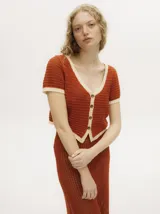 Top tejido calado color azul petróleo con cuello en V y botones carey. Tiene mangas cortas y puños en color amarillo contrastante.