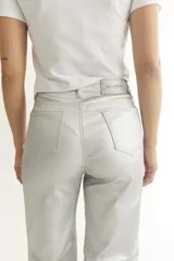 Pantalón plateado de cuerina, corte recto y cinco bolsillos funcionales.