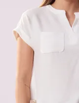 Remera blanca de tejido ribs con cuello a la base y escote en V. Tiene dos bolsillos aplicados en el frente y mangas cortas con dobladillo.