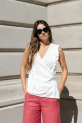 Musculosa blanca cruzada con escote en V, confeccionada en lyocell y algodón. Presenta volados en 3D en el frente y los hombros.