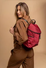 Mochila urbana de diseño compacto, color violeta/malva, con acabado ligeramente brillante. Presenta un compartimento principal con doble cierre superior y bolsillos laterales con cierre.