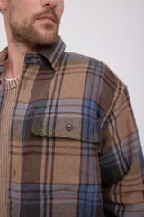 Sobrecamisa de manga larga a cuadros en tonos marrón, azul y verde. Tiene cierre con botones, bolsillos en el pecho con cierre de botón y corte relajado.