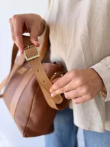 Bolso tipo tote de cuero color marrón con doble asa corta y correa larga extraíble.