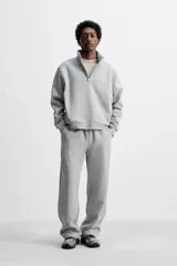 Pantalón jogger gris de corte recto, confeccionado en tejido de algodón compacto con interior en rizo. Cuenta con cintura elástica ajustable con cordón interior, bolsillos frontales y bolsillo de doble vivo en la espalda.