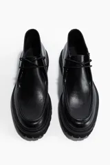 Zapato tipo bota de caña baja para hombre en color negro, con costura frontal estilo mocasín y cierre de cordones. Cuenta con una suela gruesa dentada y forro interior de algodón.