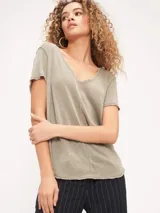 Remera color verde oliva con escote en V, corte relajado, bordes sin rematar, detalles de costura central expuesta y dobladillo estilo camisero.