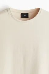 Remera color crema de corte slim fit, con cuello redondo y mangas cortas.