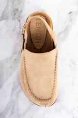 Zueco color beige de gamuza, con plantilla de corcho, detalle de costuras en la parte delantera y tira trasera ajustable con hebilla.