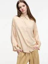 Camisa color durazno de corte amplio y fluido, con botones frontales y mangas largas.
