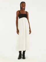 Vestido midi con tirantes finos, corte debajo del busto y falda amplia. La parte superior es negra y la falda es blanca.