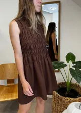 Vestido corto marrón con cuello alto, sin mangas y detalle de fruncido en la parte superior.