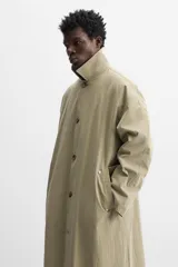 Gabardina color beige de corte amplio, con cuello solapa, manga larga, bolsillos laterales con solapa y cierre frontal con botones.