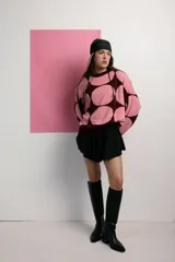 Sweater de punto color rosa con lunares grandes color borgoña, de corte holgado y cuello redondo.