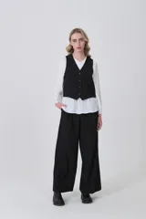 Chaleco negro de poliéster con escote en V y cierre frontal de botones. Diseño holgado.