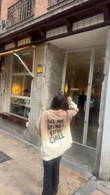 Buzo de tejido de punto color beige claro, de corte holgado y cuello redondo. Presenta un estampado grande en la espalda con texto en negro: "NO ME APURES, ESTOY CHILL".
