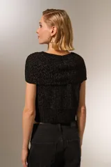 Chaleco negro de tejido de punto con lurex, cuello alto y sin mangas.