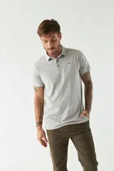 Pantalón chino color beige, de corte slim, con bolsillos laterales y traseros. Se ajusta a la cintura con cinturón de cuero marrón.