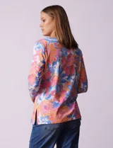 Blusa de algodón con estampado de flores en tonos rosa, naranja, azul y blanco. Tiene cuello cuadrado con borde celeste y mangas 3/4 con borde celeste.
