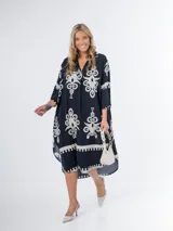 Vestido midi oversized con estampado en fondo negro, cuello tipo camisa, escote en V y tajos laterales.