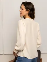 Blusa color beige de gasa con escote en V, apliques de botones y detalle de punto smock en hombro y puño.