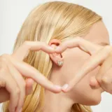 Par de aros tipo botón con forma de corazón tridimensional, acabado pulido y brillante, bañados en plata de ley.