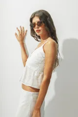 Top blanco con breteles finos y detalle de nudo en el centro del busto.