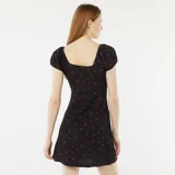 Vestido corto negro con estampado de flores rojas, escote cuadrado, mangas cortas abullonadas y cuerpo ajustado de tejido gofrado.