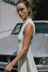Vestido largo color blanco, de cuello redondo y sin mangas. Tejido con textura y corte evasé con vuelo.