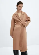 Abrigo largo color camel de lana reciclada con diseño oversize, cuello con solapa, manga larga, dos bolsillos delanteros, cinturón desmontable y abertura posterior en el bajo.