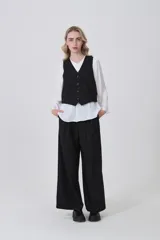 Chaleco negro de poliéster con escote en V y cierre frontal de botones. Diseño holgado.