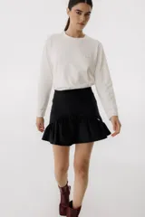 Minifalda marrón de corderoy con volados en el ruedo y etiqueta dorada con logo en la cintura.