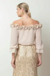 Blusa beige con escote off-shoulder con volados, mangas largas abullonadas con puños elásticos y corte ajustado.