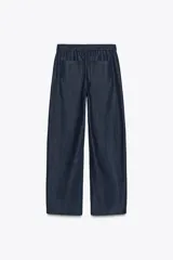 Pantalón de denim azul oscuro, de tiro medio y corte ancho, con cintura elástica en la parte trasera y cierre frontal con cremallera y botón.