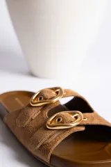 Sandalias de cuero color beige con dos tiras anchas y hebillas doradas ajustables.